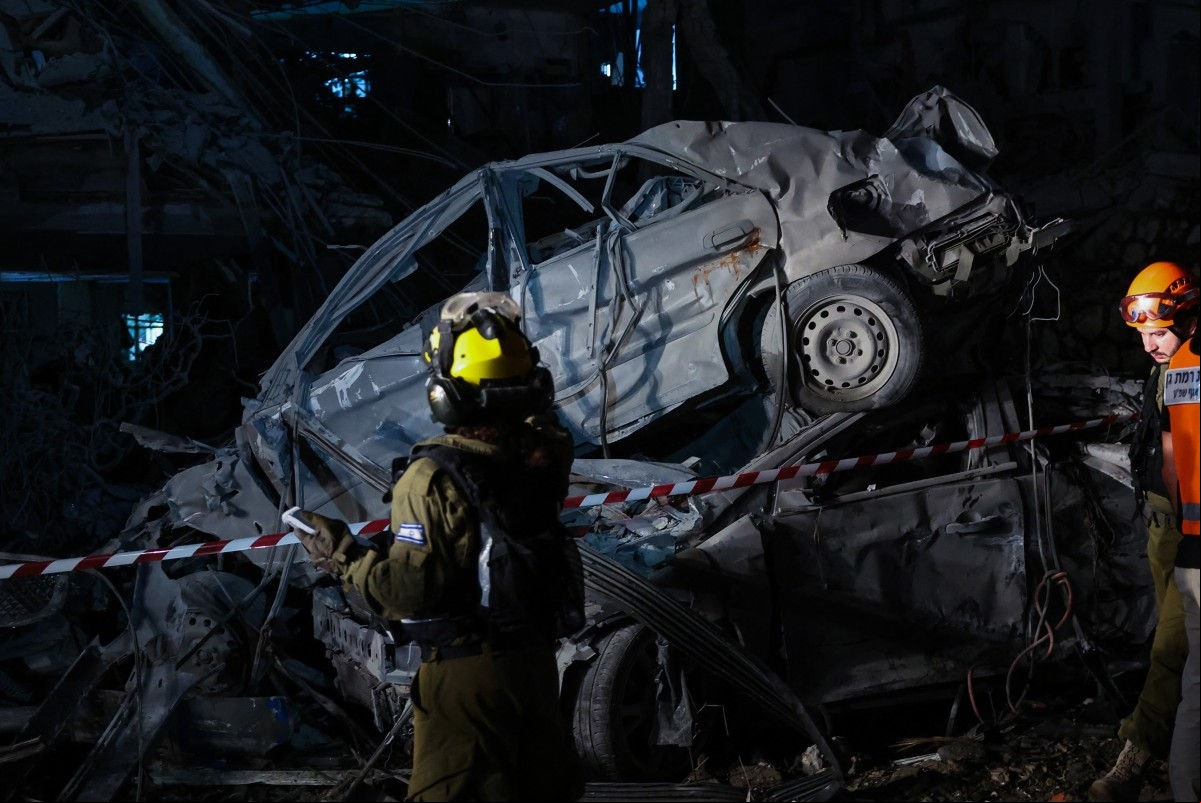 Membros das forças de segurança israelenses inspecionam um local atingido por um míssil disparado do Irã, em Ramat Gan, nos arredores de Tel Aviv